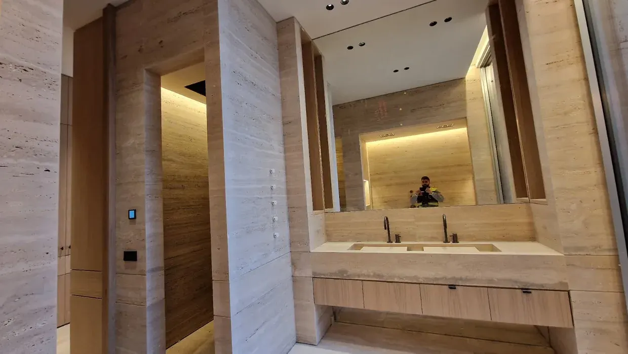 Baño completo con doble lavabo, encimera de piedra y espejos retroiluminados