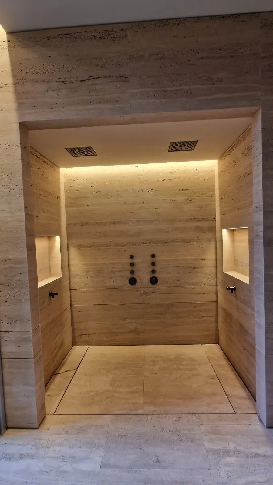 Ducha de baño revestida en travertino con iluminación LED indirecta