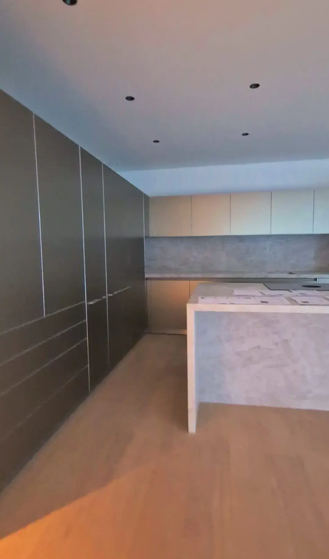Cocina reformada con isla central de piedra y armarios grises