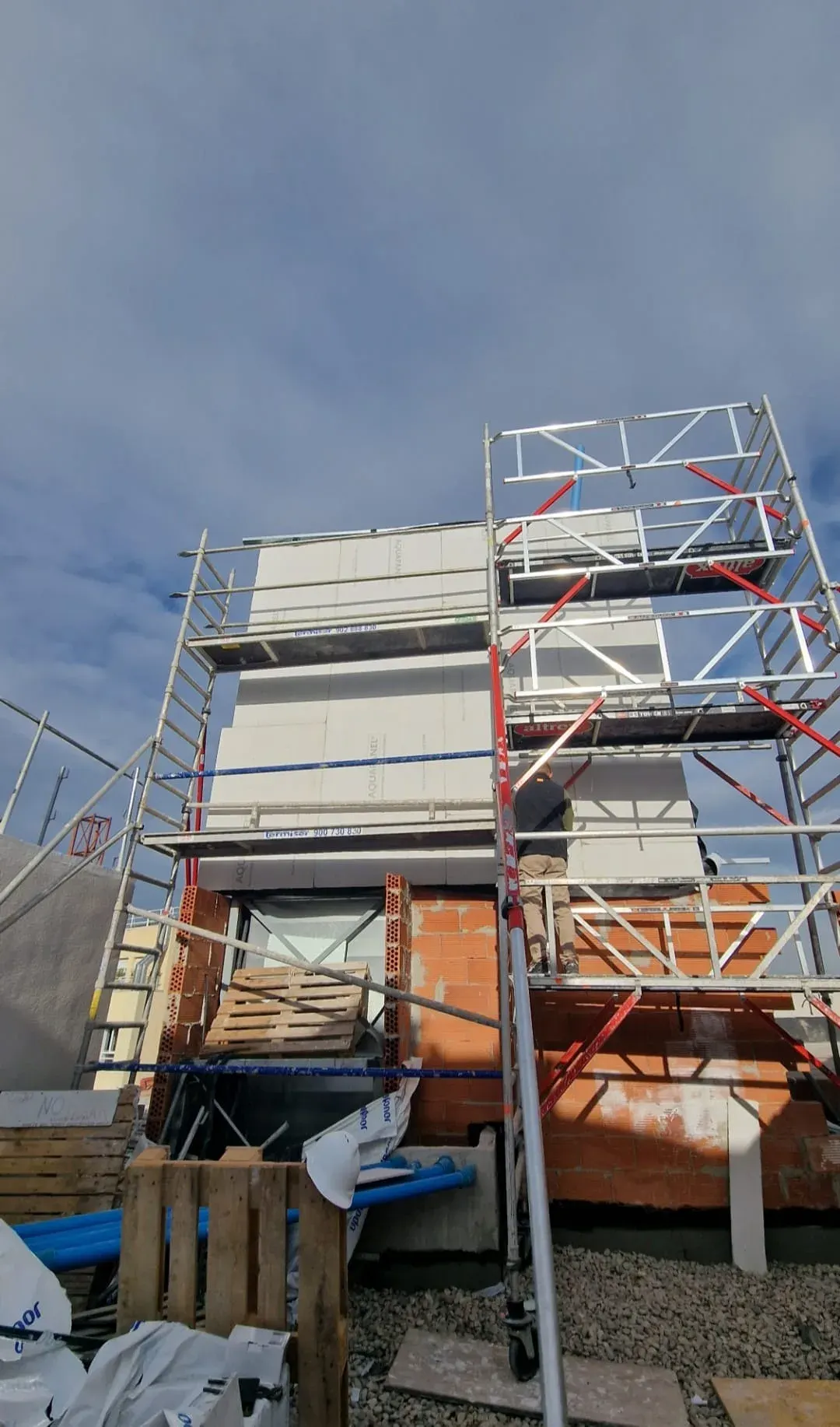 Fachada con andamios y placas exteriores en obra grande